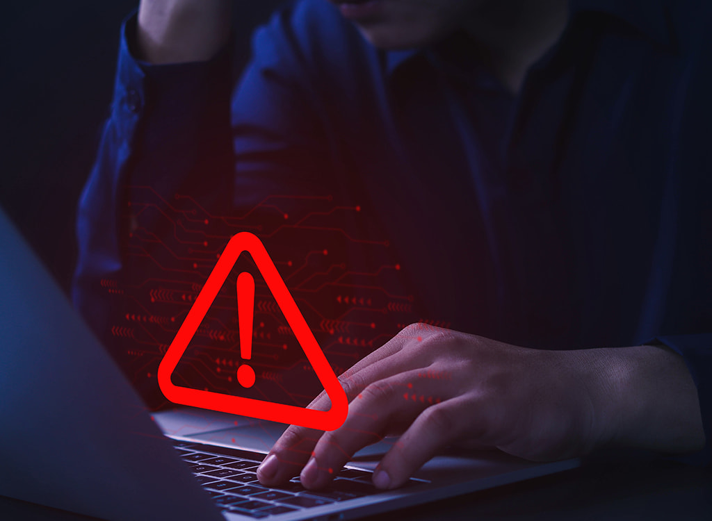 Person looking at laptop with warning sign displayed